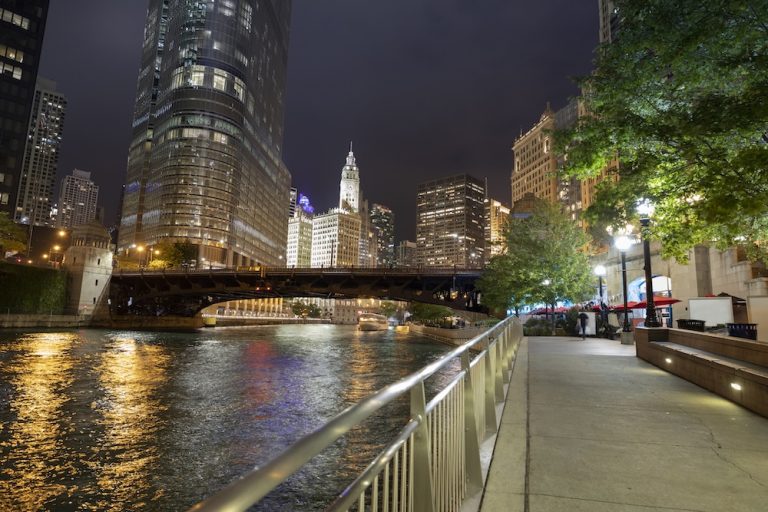 The downtown urban city view along the Riverwalk path at night on the Chicago River in Illinois USA