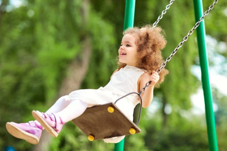 Child swinging on a swing at playground in the park. Children Protection Day.